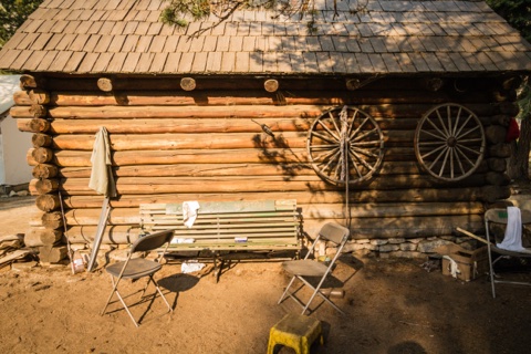 Wagon wheels and a bench on the log wall of one of the camp's historic cabins.