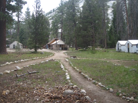 Stone-lined paths converging on the main building, tent cabins at the treeline.