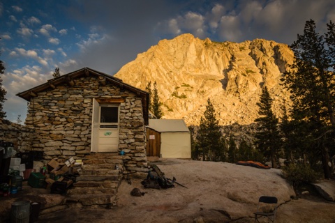 The stone building's doorway at dusk, packs resting on the granite.